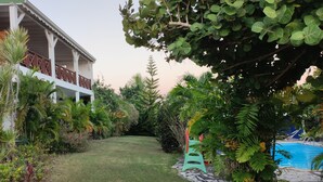 Et hus med balkon, omgivet af frodig vegetation og en swimmingpool.