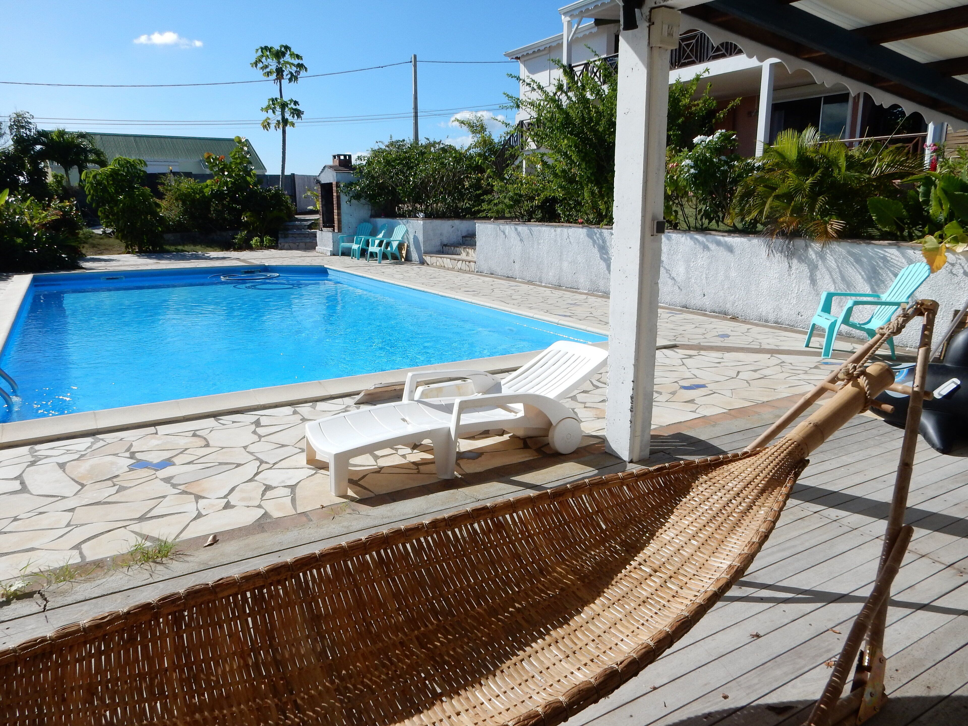 A swimming pool with lounge chairs and a hammock.