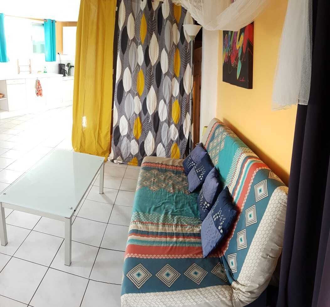 Una habitación con sofá, mesa de vidrio y cortina estampada.