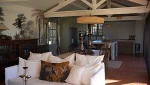 A spacious living area with a white sofa, a dining table, and a kitchen in the background. - House 12 Pers. Hamlet Dordogne (Saint-Martin-Des-Combes)