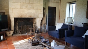 A living room with a stone fireplace, a sofa, a coffee table, and a television. - House 12 Pers. Hamlet Dordogne (Saint-Martin-Des-Combes)