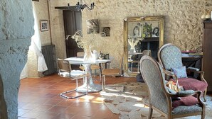 A rustic interior with exposed wooden beams, a stone wall, a round table with chairs, and a patterned rug on the floor. - House 12 Pers. Hamlet Dordogne (Saint-Martin-Des-Combes)