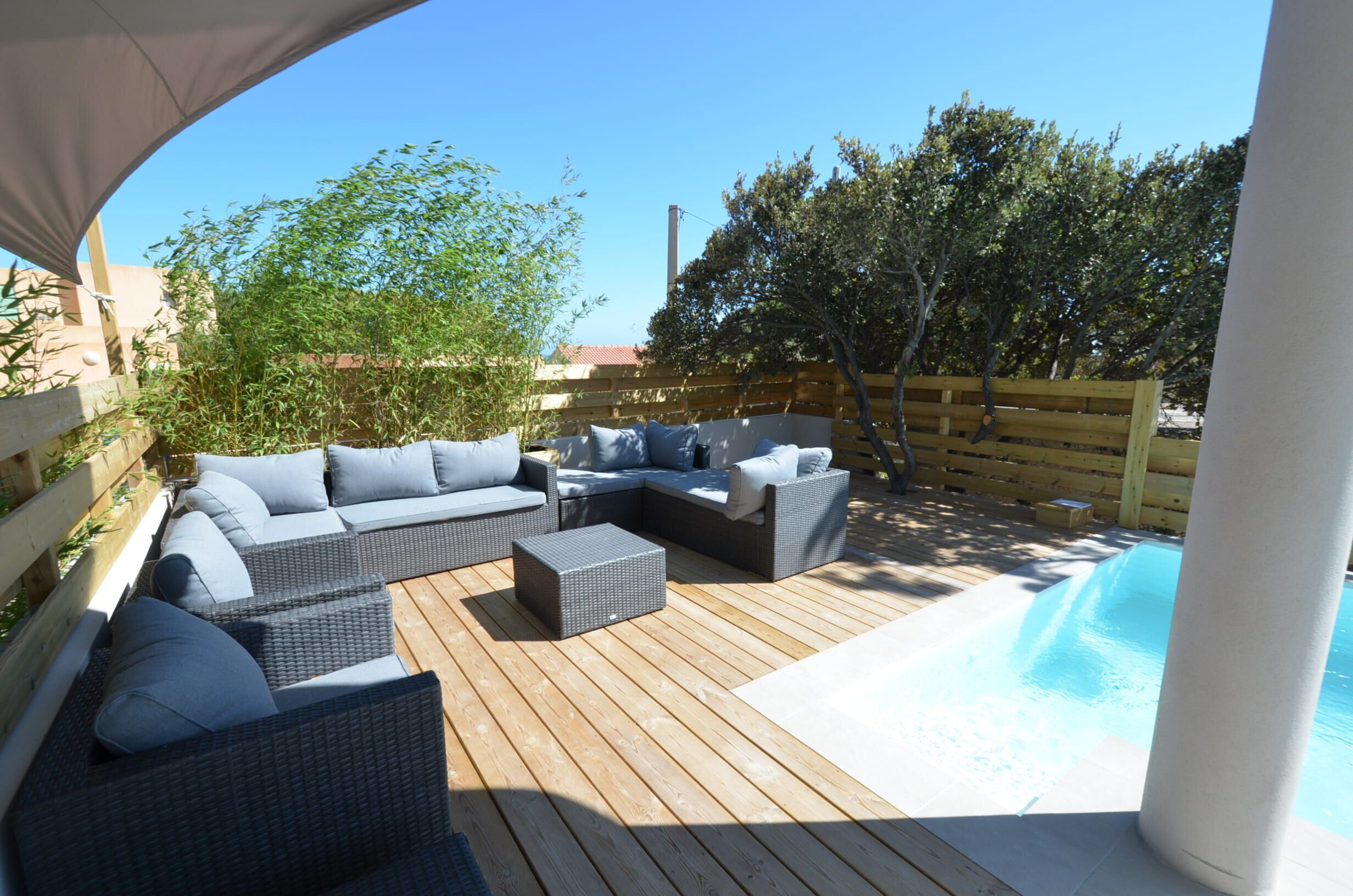 Terrassa exterior amb un sofà modular, una taula petita i una piscina.