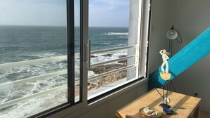 A room with a large window overlooking a rocky coastline and the ocean. - A studio located in a house directly on the beach in a stunning maritime site (Guilvinec)