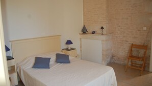Un dormitorio con cama, mesita de noche, escritorio, silla y lámpara.