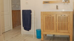 Un baño con tocador de madera, un espejo y un perchero para toallas.