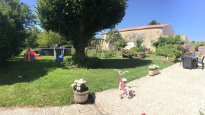 Un jardín con un columpio, una casita de juegos y una mesa de picnic.