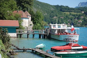 A boat docked at a pier with a mountainous backdrop. - Small house and its garden in the center of the village of Duingt 200 meters from the lake (Duingt)