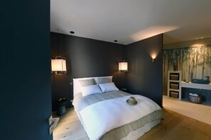 A modern bedroom with a large bed, two bedside lamps, a nightstand, and a wall-mounted shelf. - Les Loges en Provence - Villa "Ventoux (Villeneuve-lès-Avignon)