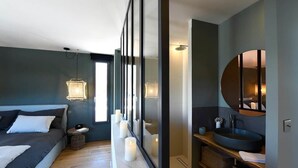 A modern bedroom with a bed, bedside table, and a large mirror. - Les Loges en Provence - Villa "Ventoux (Villeneuve-lès-Avignon)