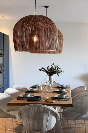 A dining area with a large woven pendant light, a central vase with greenery, and a set table with plates and glasses. - Les Loges en Provence - Villa "Ventoux (Villeneuve-lès-Avignon)