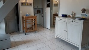 A kitchen with a wooden table, white cabinets, and a staircase. - Holiday rental 5 people ideally located in St Martin de Ré (Saint-Martin-De-Ré)