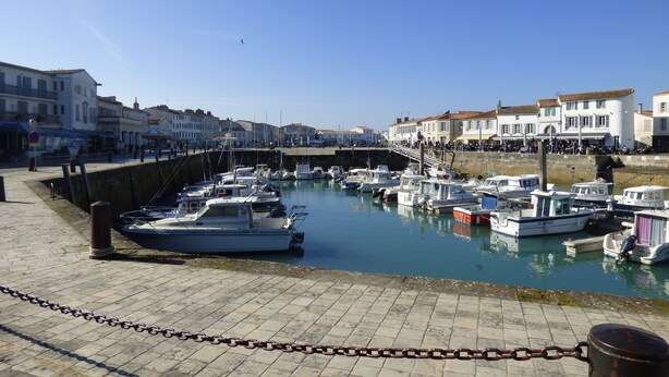 A marina with boats docked, a stone walkway, and buildings in the background. - Holiday rental 5 people ideally located in St Martin de Ré (Saint-Martin-De-Ré)