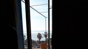 A balcony with a view of the sea, a potted plant, and a metal railing. - For six people, 1st floor of villa, sea view apartment of 80m2 (Toulon)