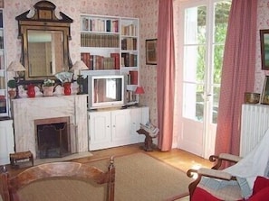 Um quarto acolhedor com lareira, estante de livros, televisão e janela com cortinas.