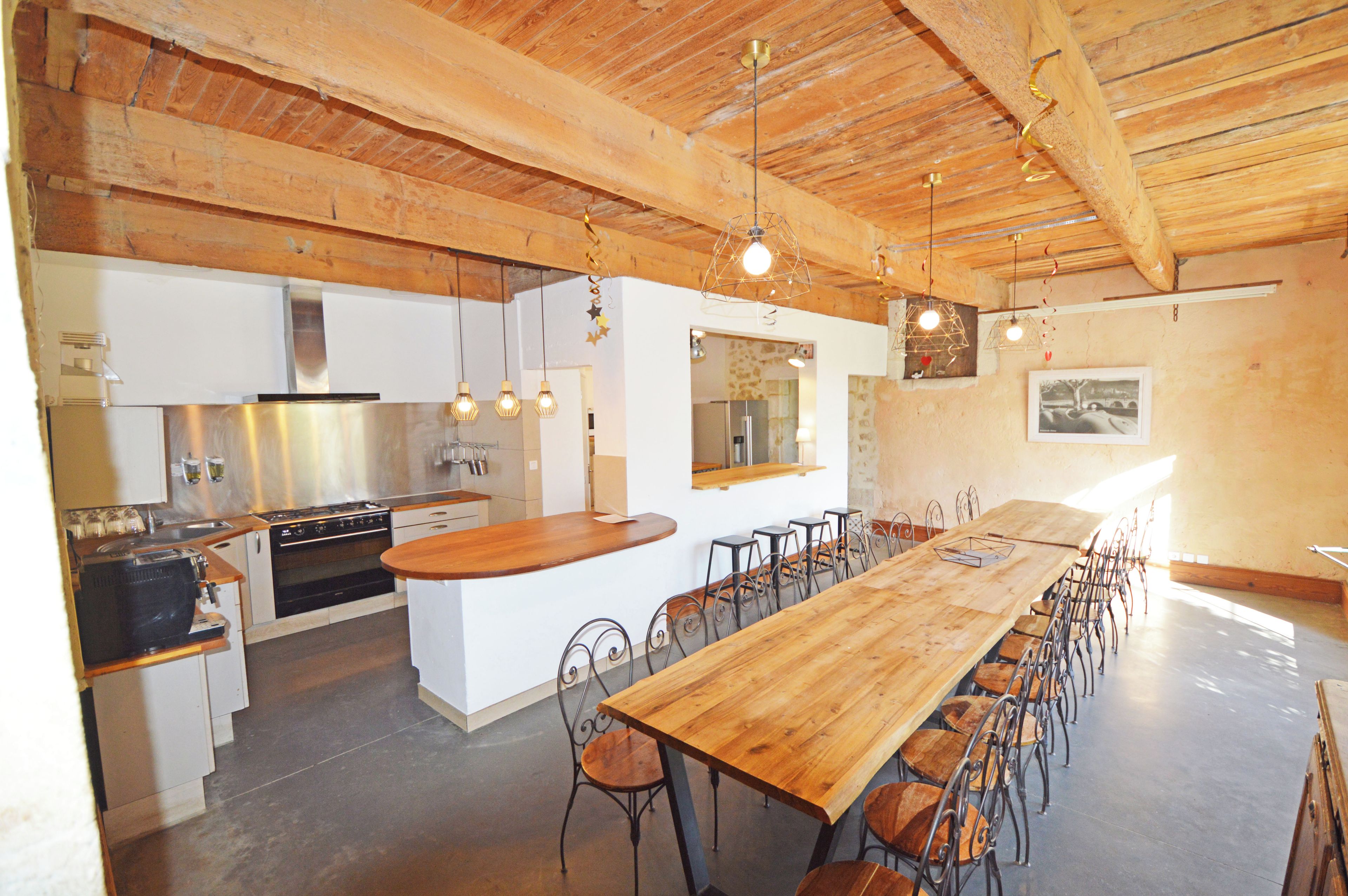 Une cuisine spacieuse équipée d’appareils électroménagers modernes, une grande table à manger en bois et un coin bar.