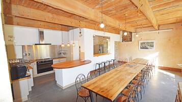 Une cuisine spacieuse équipée d’appareils électroménagers modernes, une grande table à manger en bois et un coin bar.