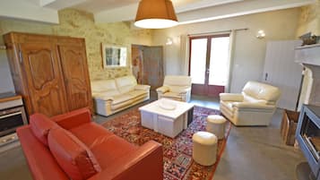 Ein Wohnzimmer mit einem roten Sofa, weißen Sesseln, einem Couchtisch und einem gemusterten Teppich.