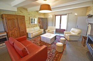 Ein Wohnzimmer mit einem roten Sofa, weißen Sesseln, einem Couchtisch und einem gemusterten Teppich.