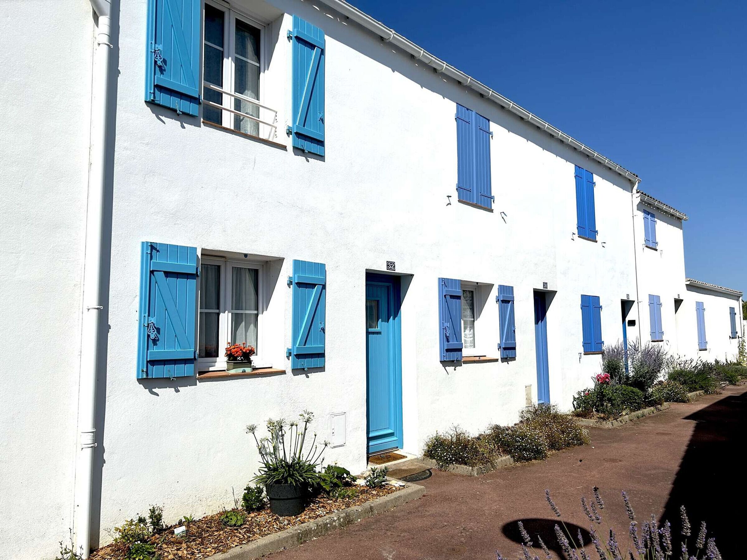 Um edifício branco com portadas azuis e janelas numeradas.