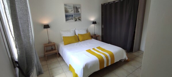 A neatly arranged bedroom with a bed, two bedside tables, and a wall-mounted picture.