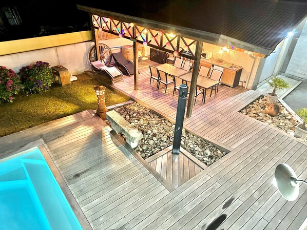 A patio area with a pool, wooden deck, and outdoor seating.