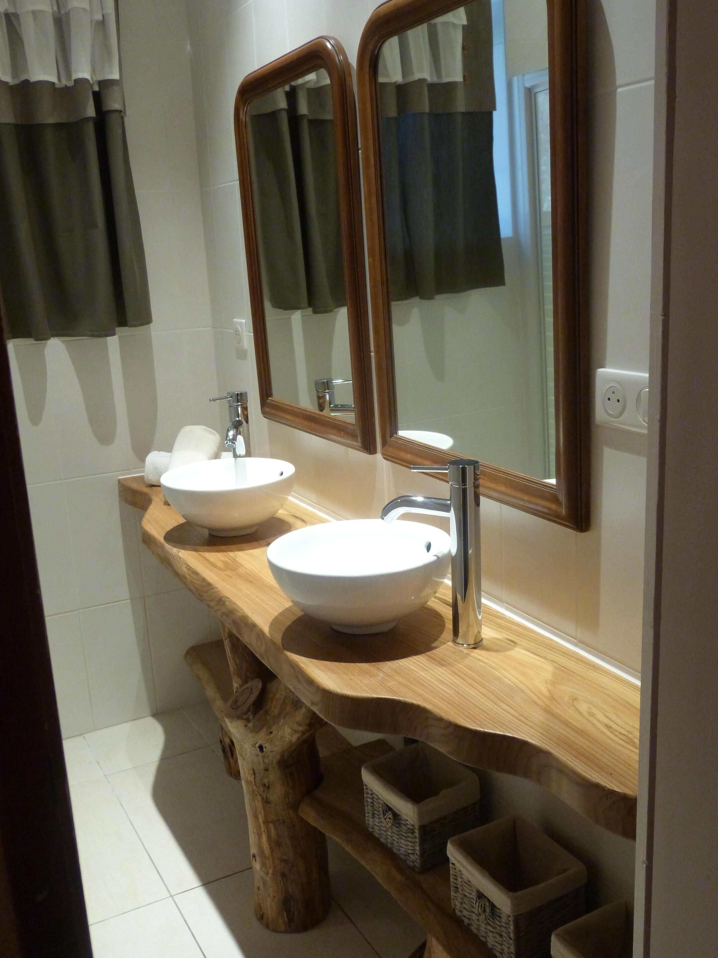 A bathroom with a wooden vanity, two sinks, and a large mirror.