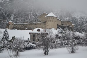 Un edificio histórico con techo nevado y árboles circundantes.