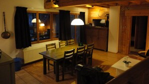 Ein Essbereich mit einem Holztisch, Stühlen, einer Lampe und einem Fernseher auf einer Holzkommode.