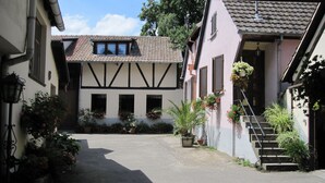 Une rue étroite bordée de bâtiments des deux côtés, où l’on peut admirer un mélange d’architecture traditionnelle et moderne, notamment un bâtiment doté d’un toit en pente et un autre avec une façade plate.