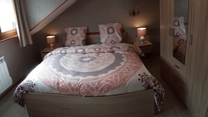 Une chambre à coucher avec un grand lit, une armoire en bois et une petite table de chevet avec une lampe.