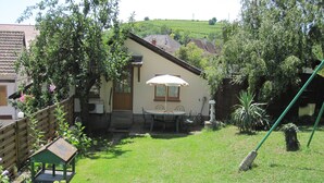 Une petite maison avec une terrasse, une table et des chaises.