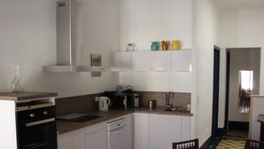 A compact kitchen with white cabinets, a coffee maker, a toaster, and a sink. There is a dining area with a table and chairs. - TYPICAL HOUSE IN THE HEART OF THE VILLAGE, ENTIRELY RENOVATED, 200M FROM THE BEACH (Le Barcarès)