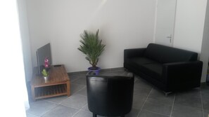 Relax in this stylish living room with a black leather sofa, coffee table, and lush greenery.