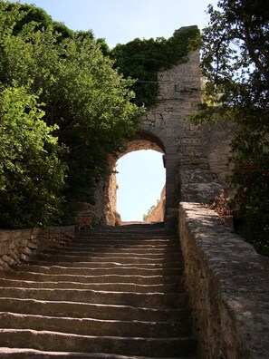 A stone staircase leading to an arched stone structure surrounded by greenery. - Gite rental, a stopover in the Luberon (Bonnieux)