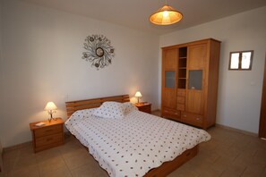 Ein Schlafzimmer mit einem Bett, Nachttischen, einem Holzschrank und einer Wanddekoration.