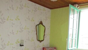 A room with a bed, a chair, a mirror, and a window with curtains. - independent house in property retaise for 4 people (Le bois plage)
