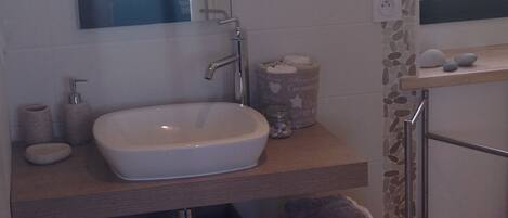 A bathroom with a white sink, a mirror, a towel rack, and storage boxes.