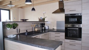 Eine moderne Küche mit Holzausstattung, einer Granit-Arbeitsplatte, Edelstahlgeräten und Pendelleuchten.