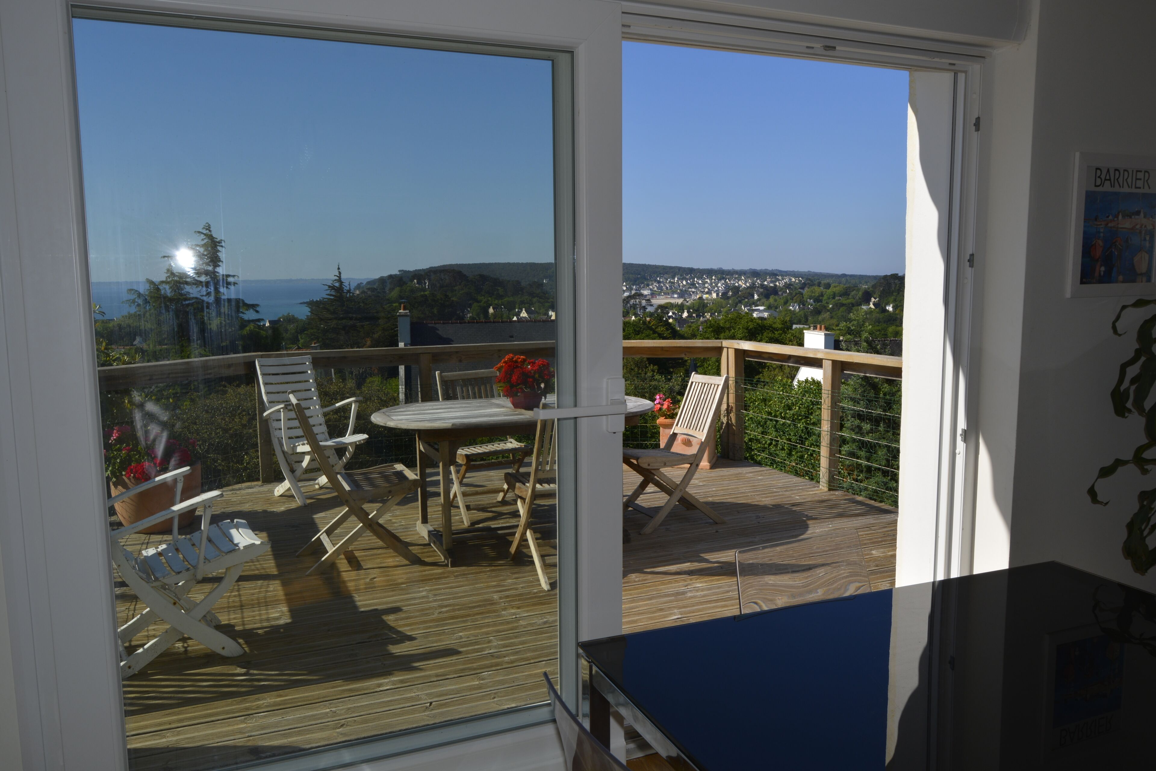 Ein Balkon mit Tisch und Stühlen, der einen schönen Blick auf eine Stadt und das Meer bietet.