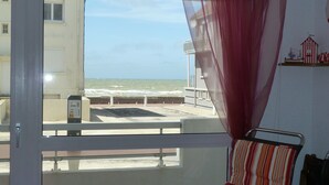 A room with a view of the sea through a window, a chair, and a curtain. - Sea view at Fort Mahon Plage in the Somme studio 4 people (Fort-Mahon-Plage)