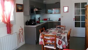 A compact living space with a dining area, kitchenette, and a cozy red couch. - Sea view at Fort Mahon Plage in the Somme studio 4 people (Fort-Mahon-Plage)