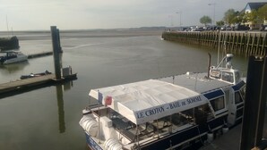A boat docked at a pier with a covered seating area and a sign reading "LE CROTOY - BAIE DE SOMME". - Sea view at Fort Mahon Plage in the Somme studio 4 people (Fort-Mahon-Plage)