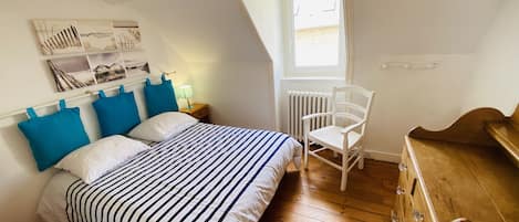 Une chambre à coucher avec un lit, une chaise, une commode et une fenêtre.