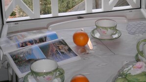 A balcony with a view of a coastal area, featuring a table with a cup, saucer, and orange, and a postcard. - Villa 3 bedrooms / Walking distance / Sea view / Beach 200 m (Perros-Guirec)