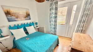 A bedroom with a bed, a nightstand, a radiator, a window with curtains, and a wooden cabinet. - Villa 3 bedrooms / Walking distance / Sea view / Beach 200 m (Perros-Guirec)