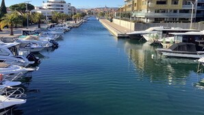 A marina with boats docked along a canal, surrounded by modern buildings and palm trees. - Bright 52m2 air-conditioned apartment with Wifi and single-storey closed garage (Fréjus)