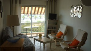 A living room with a sofa, two armchairs, a coffee table, a TV, and a bookshelf. - Bright 52m2 air-conditioned apartment with Wifi and single-storey closed garage (Fréjus)
