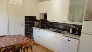 A compact kitchen with white cabinets, a black tiled backsplash, a stainless steel sink, and a white dishwasher. - Spacious apartment in chalet with a beautiful view! (Allos)