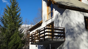 A chalet with a wooden balcony, a mountain backdrop, and a clear blue sky. - Spacious apartment in chalet with a beautiful view! (Allos)